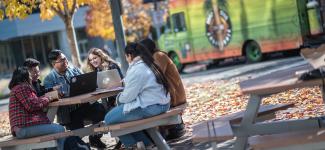 A group of students sitting together at a picnic table at UBC Okanagan campus